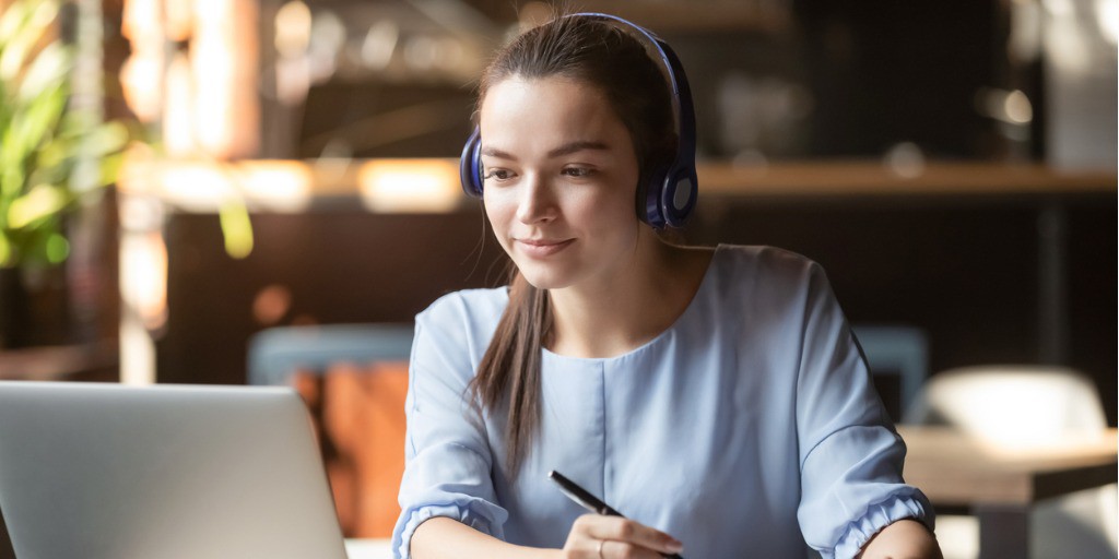 focused-woman-wearing-headphones-using-laptop-writing-notes-picture-id1152767923 woman concentrating while learning from home