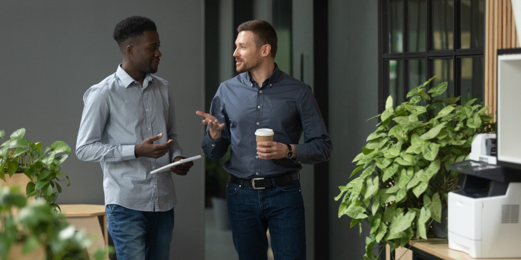 diverse-friendly-male-partners-talking-walking-in-office-hallway-picture-id1171786270 male co-workers chatting at work